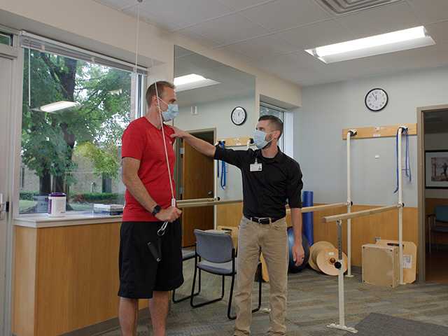 Healthcare provider assisting man with movement